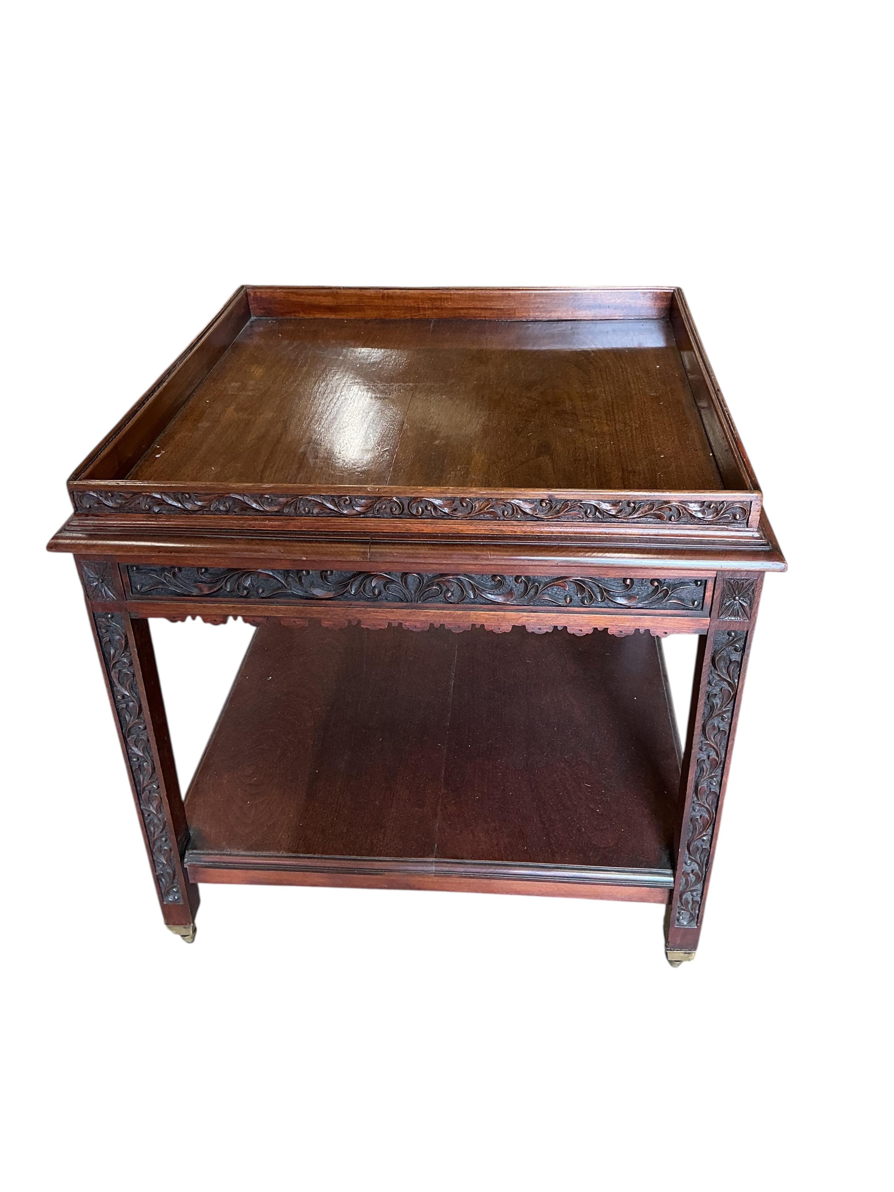 An early 20th century carved walnut square two tier occasional table, with brass caps and casters, 76cm, height 76cm